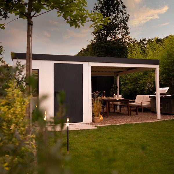 Gartenhaus mit überdachter Terrasse, Gartentisch und Grillplatz in einem gepflegten Garten.