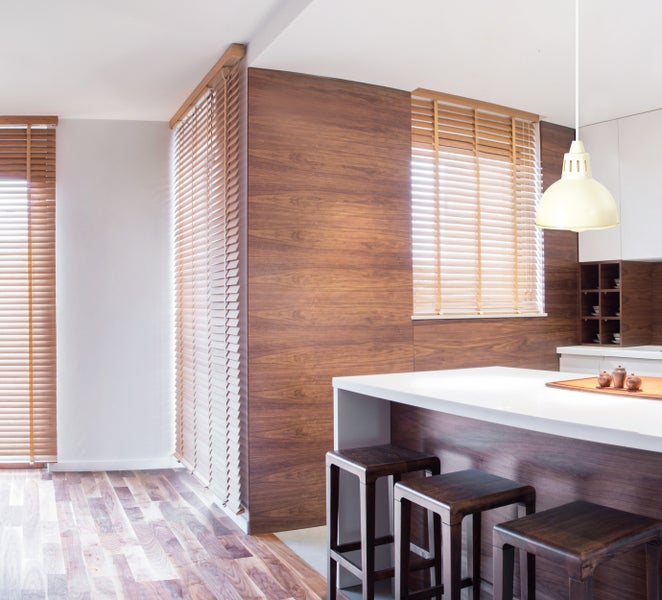 Innenaufnahme einer Küche mit Holzböden, Holzjalousien und Barhockern
