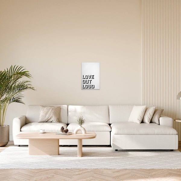 Wohnzimmer mit Ecksofa, Couchtisch und einem Poster mit dem Schriftzug Love Out Loud
