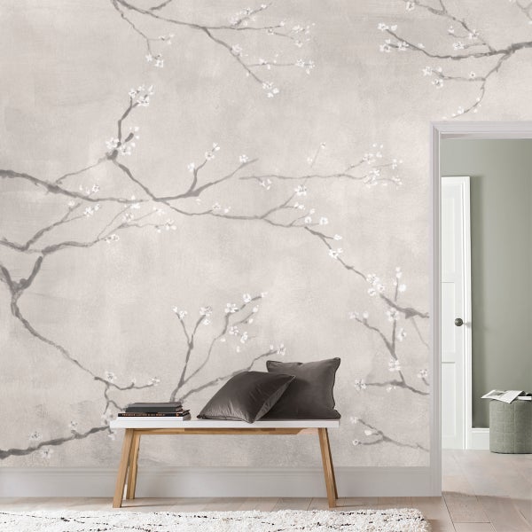 Vliestapete mit zartem Kirschblütenmotiv auf strukturierter Wand in einem modern eingerichteten Flur mit Holzbank und Kissen.