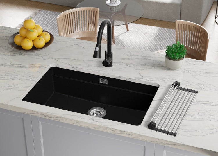 Schwarzes Spülbecken mit Abtropfgestell und Armatur auf einer Küchentheke.