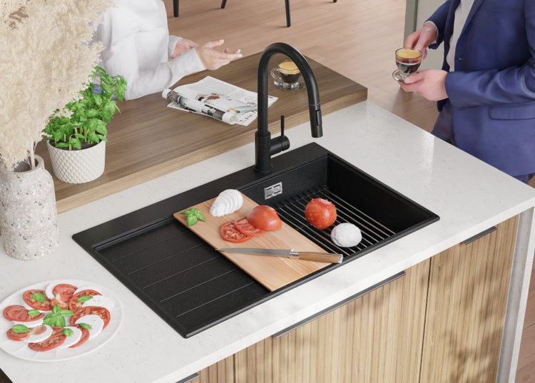 Schwarze Küchenspüle mit Armatur und Zutaten für Caprese-Salat auf der Arbeitsfläche.