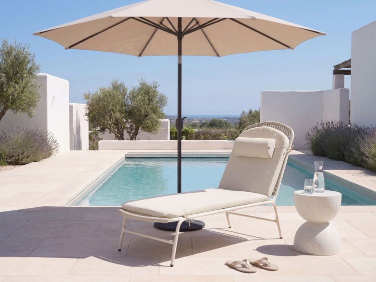 Sonnenliege mit Kissen und Sonnenschirm an einem Pool auf einer Terrasse mit modernem Beistelltisch.
