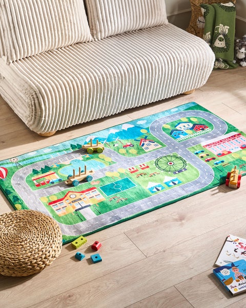Spielteppich mit Stadtmotiv neben Sofa und Spielsachen