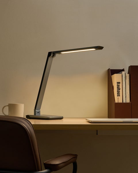 Schreibtischszene mit LED-Tischleuchte, Tasse und Büchern