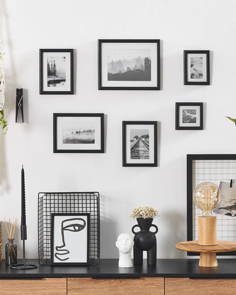 Wanddekoration mit Bilderrahmen in verschiedenen Größen und Designs über einem Sideboard