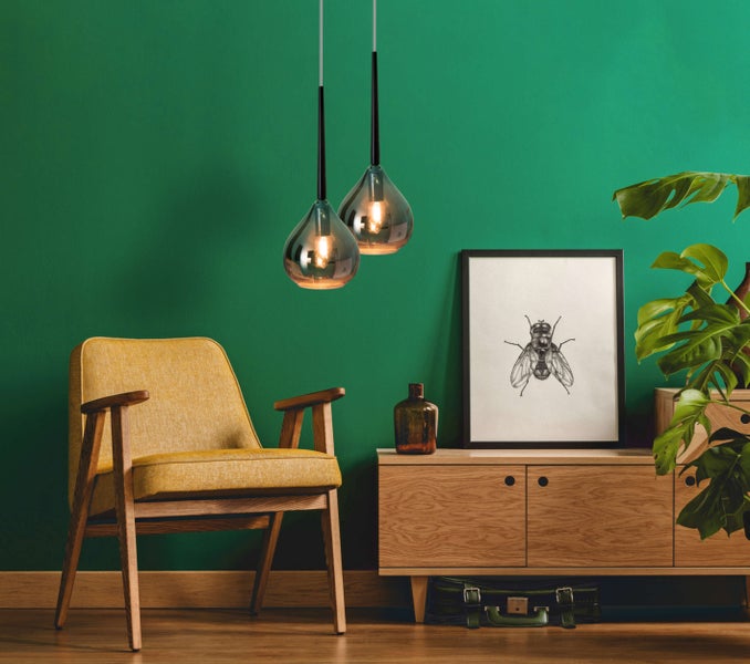 Wohnzimmer mit Sessel, Kommode, Zimmerpflanze und zwei Pendelleuchten