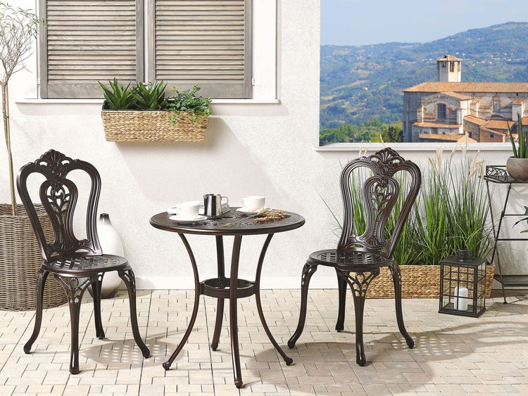 Gartenmöbel-Set mit Tisch und zwei Stühlen auf einer Terrasse mit Pflanzen und Blick auf eine Landschaft
