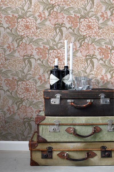 Dekoratives Interieur mit geblümter Tapete und gestapelten Vintage-Koffern