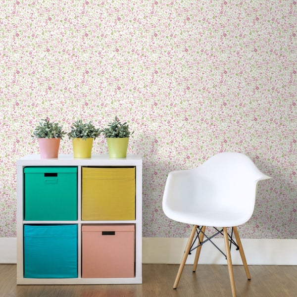 Vliestapete mit kleinteiligem Blumenmuster in Pink und Grün, weißes Regal mit bunten Aufbewahrungsboxen und weißer Schalenstuhl.