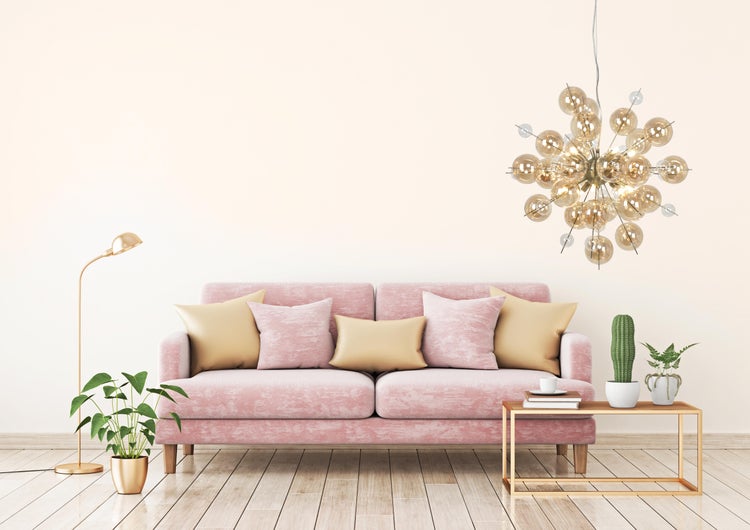 Wohnzimmer mit rosa Sofa, Couchtisch, Stehlampe und Zimmerpflanzen unter einer modernen Hängeleuchte