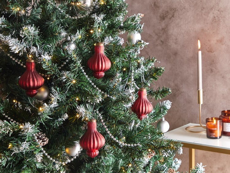 Geschmückter Weihnachtsbaum mit roten geriffelten Glasanhängern, silbernen Kugeln, Perlenkette und Lichterkette.