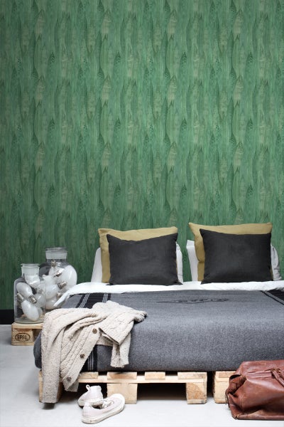 Schlafzimmer mit gemusterter Tapete, Bett aus Paletten und dekorativen Elementen.