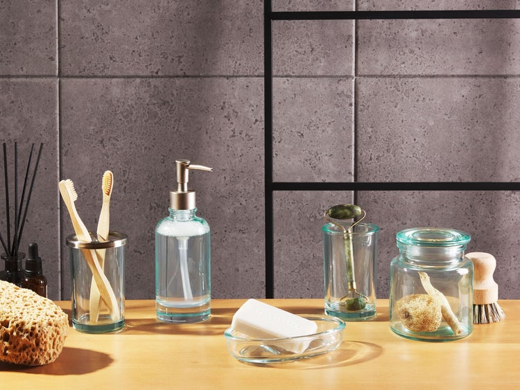 Badezimmerzubehör auf einem Holztisch, darunter Seife, Lotionspender und Zahnbürsten