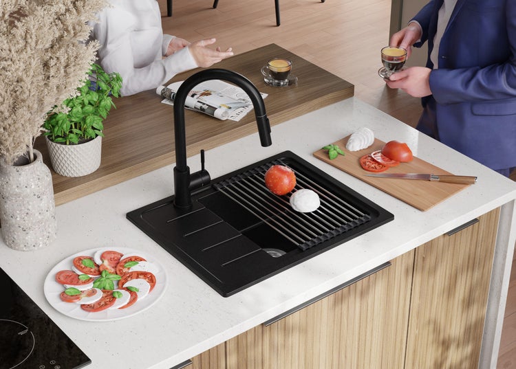 Schwarzes Spülbecken mit Abtropfgestell, Armatur und Zubereitung von Speisen in einer modernen Küche.