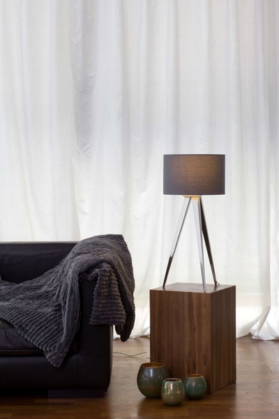 Szene mit Sofa, Decke, Stehlampe und dekorativen Vasen vor einem Vorhang