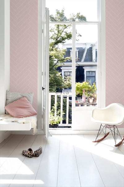 Heller Raum mit rosa Tapete, Sitzgelegenheit und geöffneter Tür zum Balkon