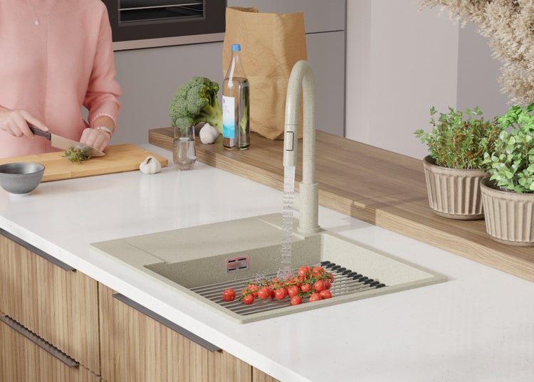 Küchenszene mit Spüle, Armatur, Gemüse und Person beim Kochen.