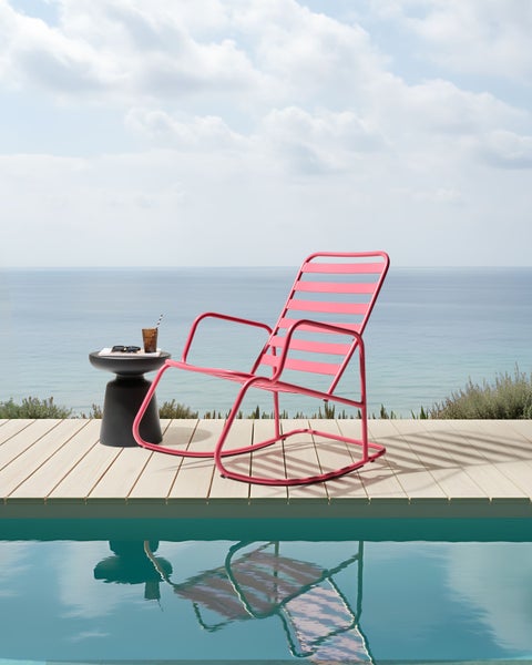 Szene mit einem Schaukelstuhl, einem Beistelltisch und einem Getränk am Pool mit Meerblick.