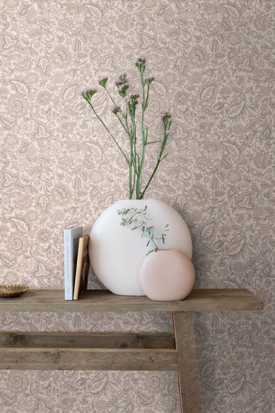 Helles Esszimmer mit einer Vliestapete mit Paisley-Muster. Ein runder Holztisch, Stühle und ein Kaminofen ergänzen die Wandgestaltung.