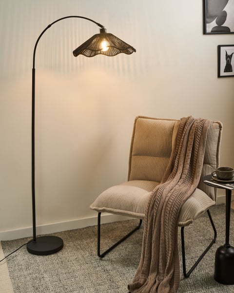 Stehlampe neben Sessel mit Decke und Beistelltisch mit Tasse