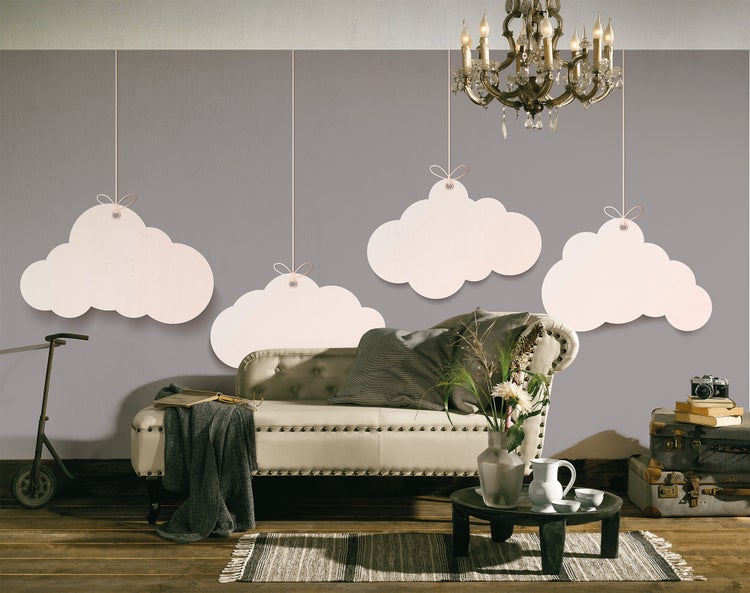 Wohnraumszene mit grauer Wand und vier hängenden Wolken-Elementen. Mit einer gesteppten Récamiere, Kronleuchter und rustikalem Holzboden.