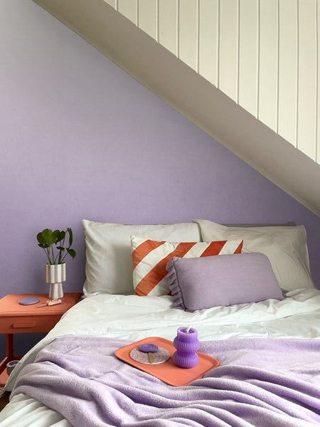 Schlafzimmer mit Bett, Kissen, Decke und Nachttisch im Dachgeschoss