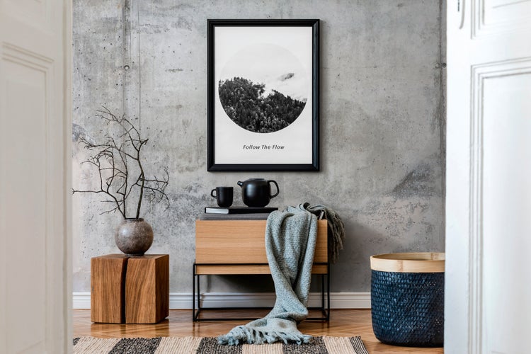 Modernes Wohnzimmer mit Betonwand, gerahmtem Poster mit Landschaftsmotiv, Holzmöbeln und Wohnaccessoires im industriellen Stil.