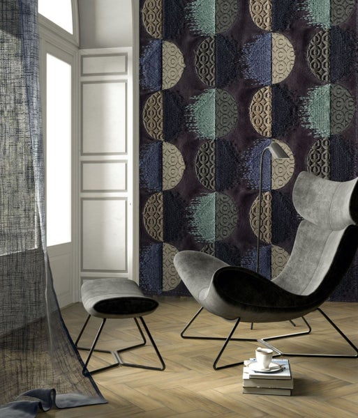 Wohnzimmer mit Sessel, Hocker, Stehlampe und gemusterter Tapete