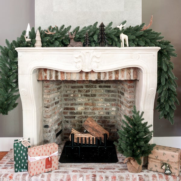 Dekorativer Kamin mit Tannengirlande, Weihnachtsdekoration und Geschenken für eine festliche Atmosphäre