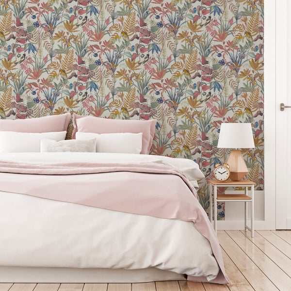 Vliestapete mit botanischem Muster aus Farnen und Vögeln in einem Schlafzimmer mit Holzfußboden und Bett mit weiß-rosa Bettwäsche.
