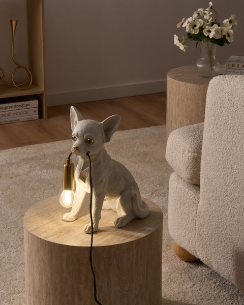 Tischleuchte in Form einer sitzenden Chihuahua-Figur aus Kunstharz auf einem Holzbeistelltisch in einem modern eingerichteten Wohnzimmer.