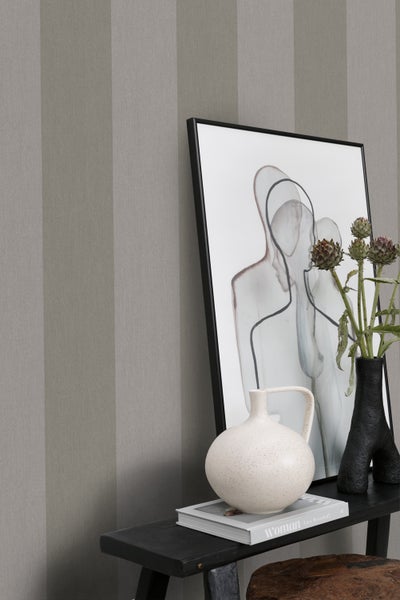 Dekorative Szene mit gestreifter Tapete, gerahmtem Kunstwerk, Vasen und Beistelltisch.