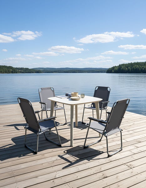 Quadratischer Gartentisch mit vier Gartenstühlen auf einer Holzterrasse am See