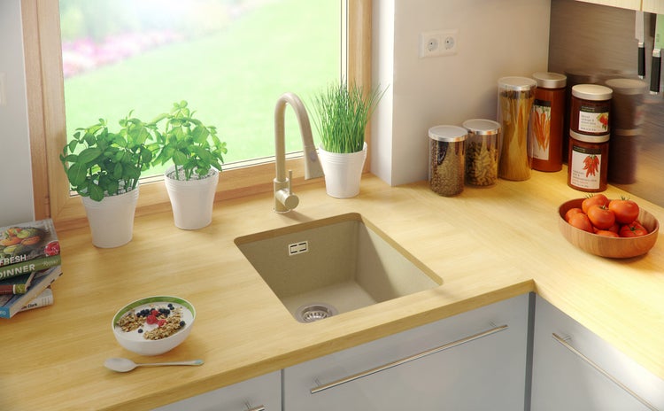 Küchenspüle aus Stein mit Armatur und Lebensmitteln auf der Arbeitsfläche