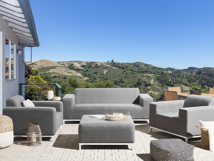 Graue Gartenmöbel-Loungegruppe auf einer Terrasse mit Ausblick auf eine hügelige Landschaft