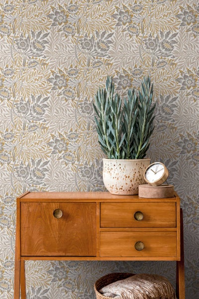 Innenaufnahme eines Wohnzimmers mit einem Teppich, einer Kommode, einem Sessel und einer Zimmerpflanze.