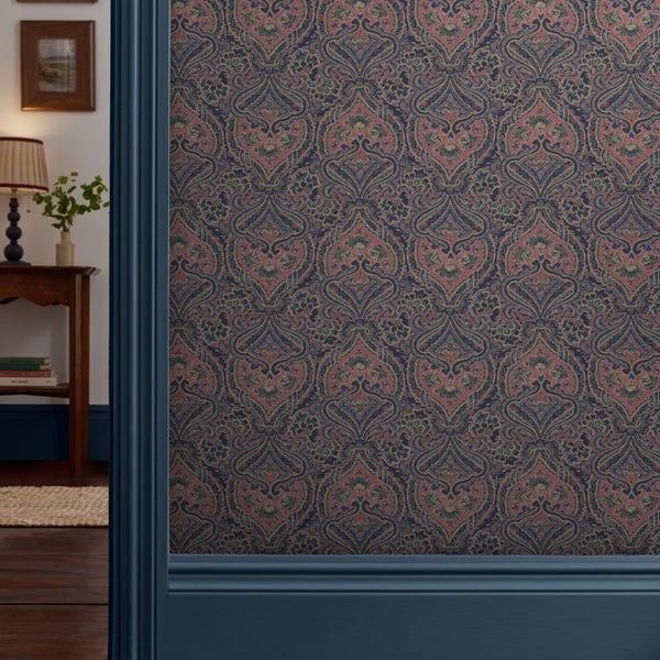 Mustertapete mit feinem Paisley-Design im klassischen Stil, kombiniert mit dunkler Holzverkleidung und Blick in ein gemütliches Zimmer.