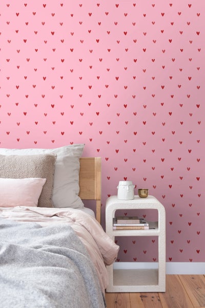 Schlafzimmer mit Bett und Wandtapete mit Herzmuster