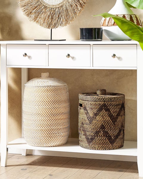 Dekoratives Arrangement auf einem weißen Konsolentisch mit geflochtenen Aufbewahrungskörben