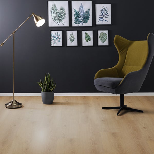 Einrichtungsbeispiel mit Stehlampe, Zimmerpflanze, Bilderrahmen und Sessel auf einem hellen Holzboden