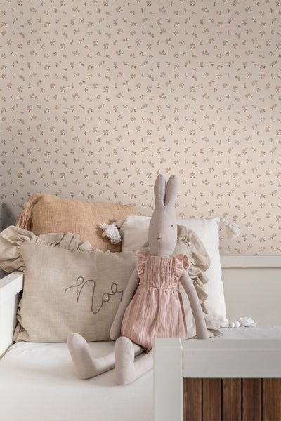 Vliestapete mit feinem Blumenmuster im hellen Kinderzimmer mit weißem Bett, Kissen und Kuscheltier.