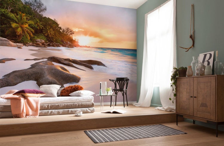 Wohnzimmer mit Fototapete, die einen Strand bei Sonnenuntergang zeigt, inklusive Sofa und Kommode