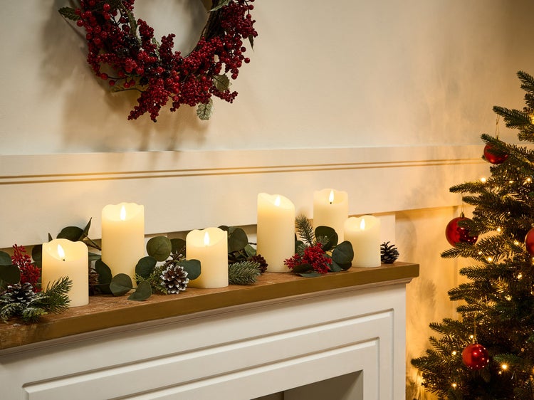 Dekorativer Kamin mit LED-Kerzen, Beerenzweigen, Tannenzapfen und Weihnachtskranz