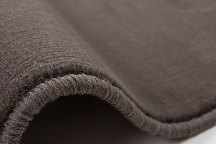 Detailansicht eines anthrazitfarbenen Teppichs mit gekettelter Kante und weicher Oberflächenstruktur.