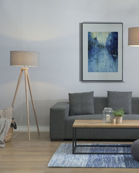 Wohnzimmer mit grauem Sofa, Couchtisch, Stehlampe und gerahmtem Bild