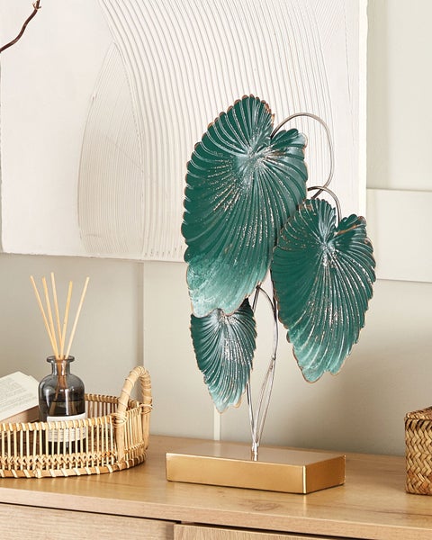 Dekorationsobjekt mit Blättern auf goldenem Sockel auf einer Kommode