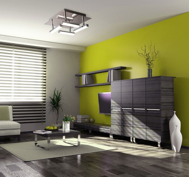 Modernes Wohnzimmer mit Deckenleuchte, Couch, Sessel, Teppich und Regalen