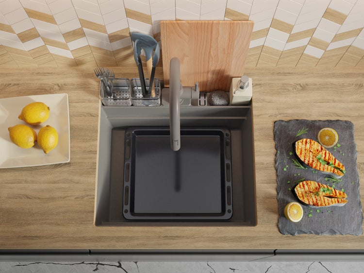 Küchenspüle mit Abtropffläche, Armatur, Schneidebrett und Geschirr auf einer Arbeitsplatte