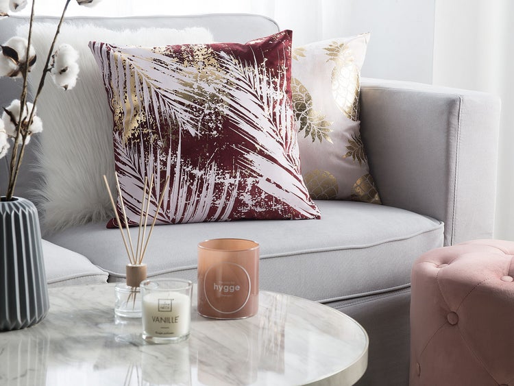 Dekoratives Wohnzimmerambiente mit Kissen, Duftkerze und Blumenvase auf Couchtisch